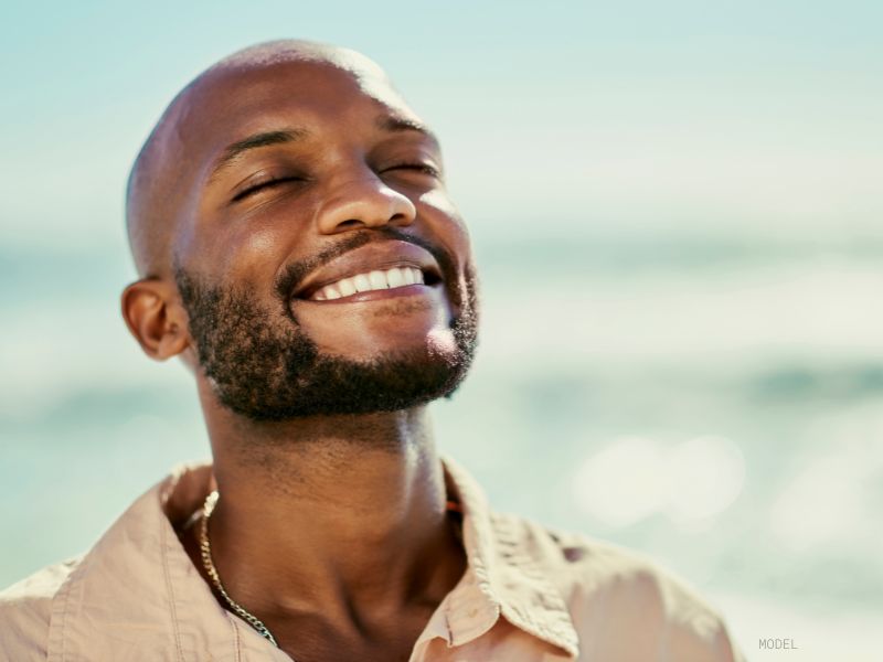 man standing at beach smiling showing off his fillers (Model)