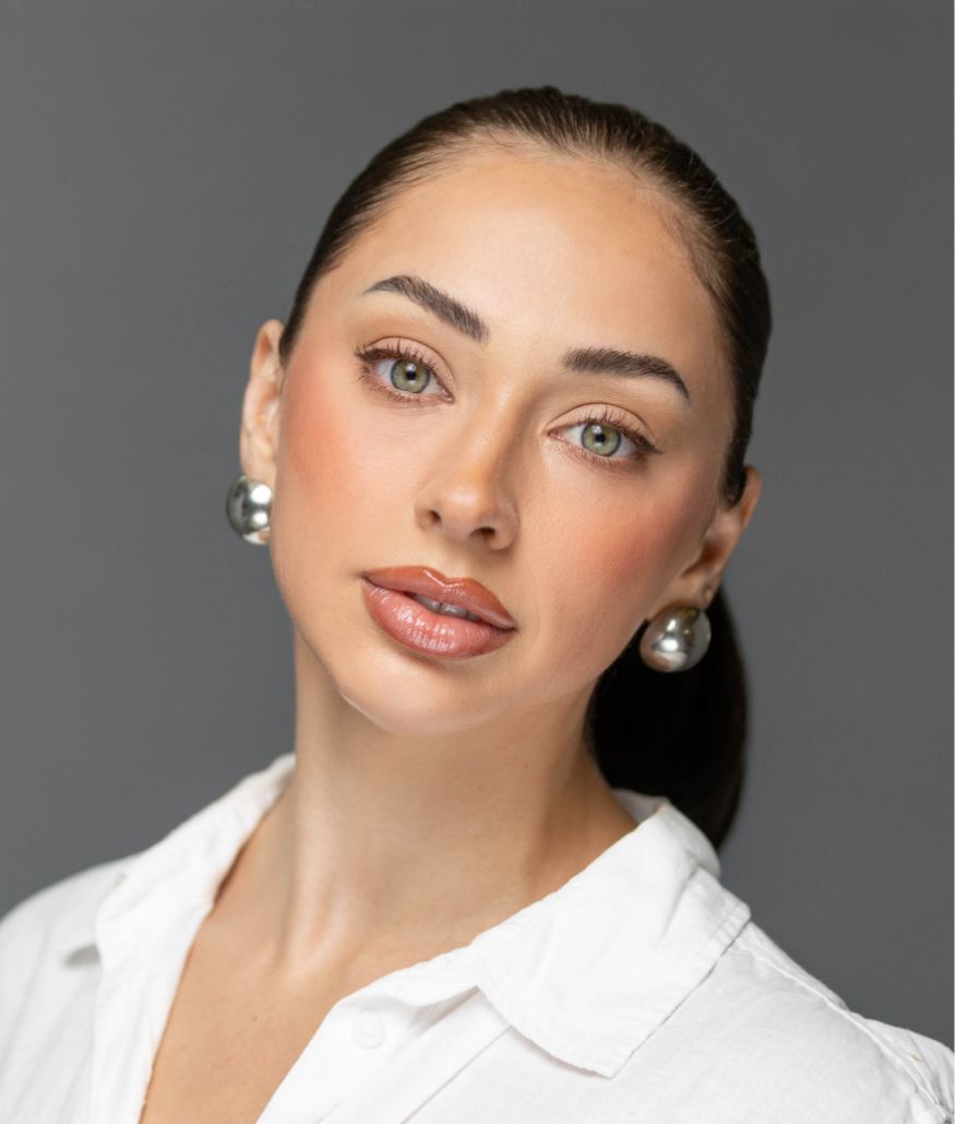 Studio portrait of woman with sleek hair and pearl earrings on gray background