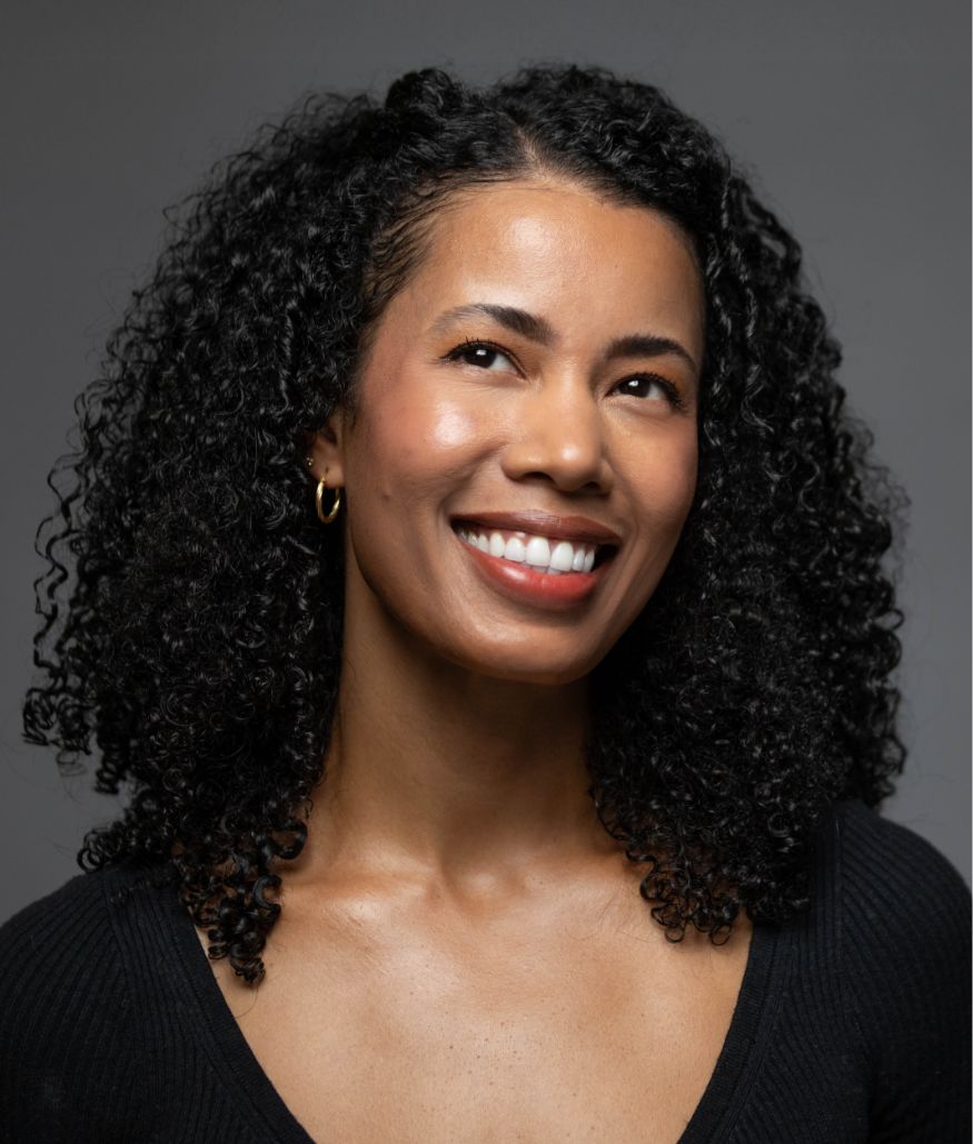 Studio portrait of smiling woman with curly hair on gray background