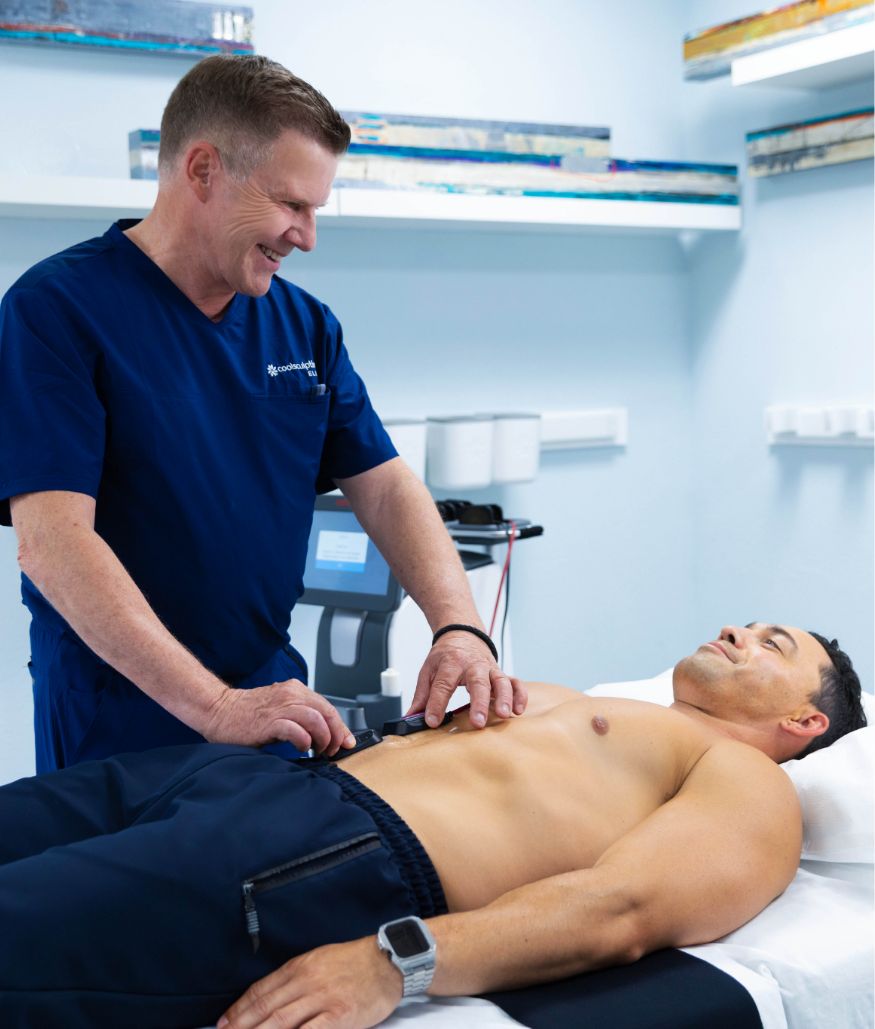 Clinician performs body contouring treatment on male patient in exam room