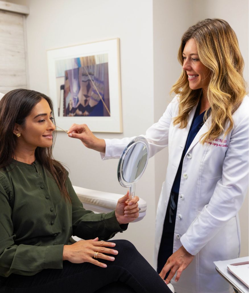 Patient holds mirror and examines face during consultation