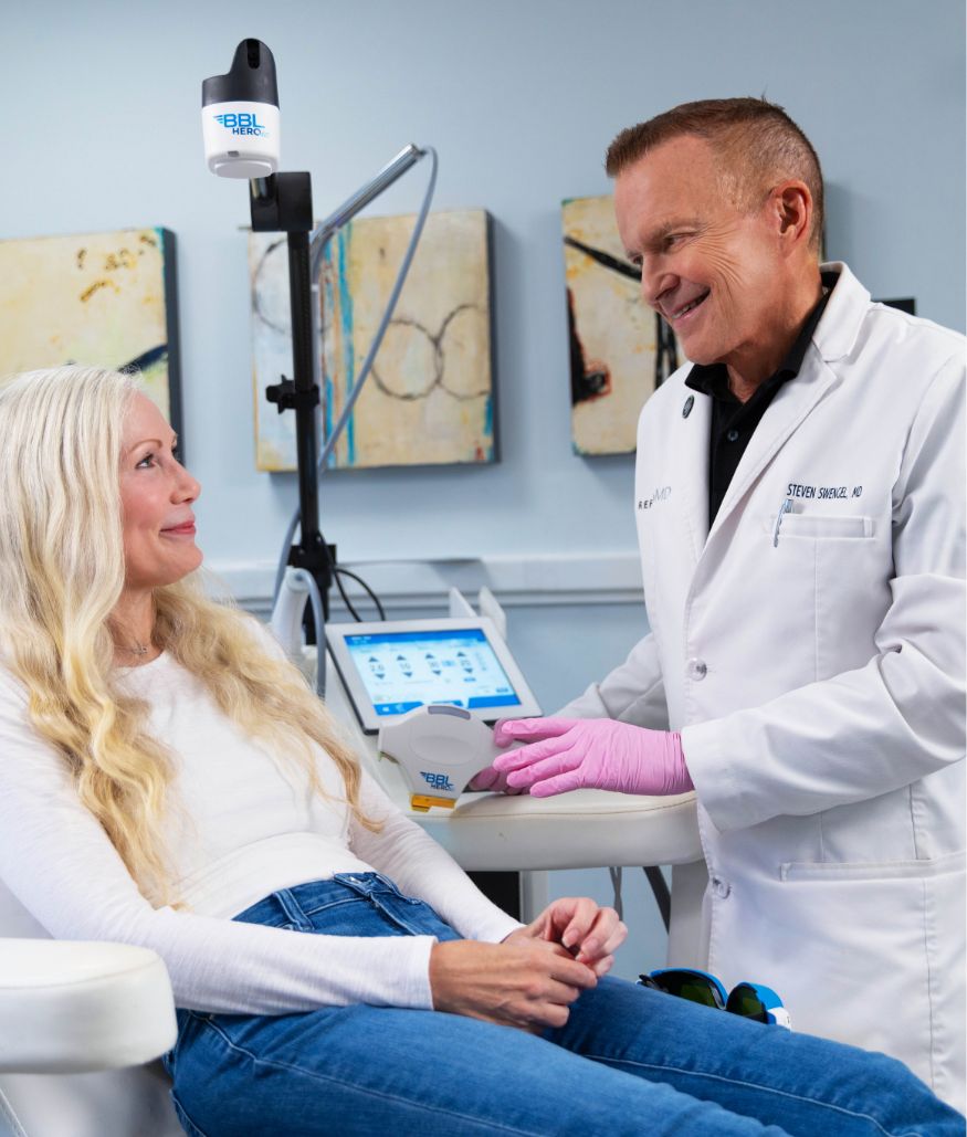 Dr. Swengel in white coat consults with seated patient beside laser device
