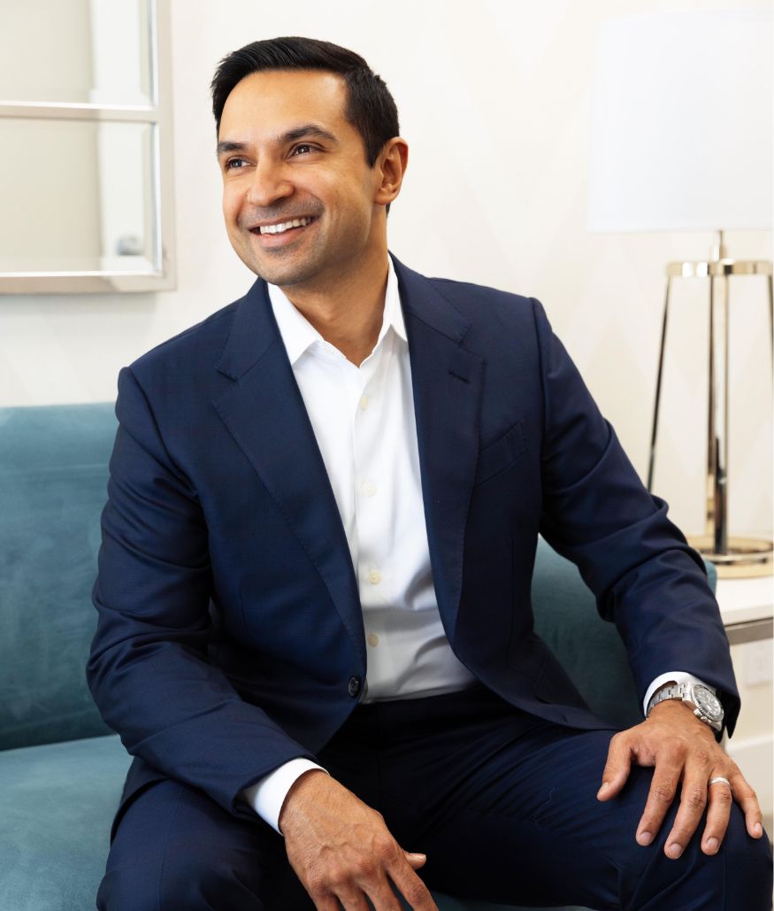Dr. Roy in a suit, smiling, while seated in office lounge