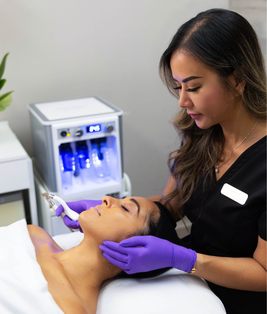 Esthetician performs facial treatment with handheld device on client