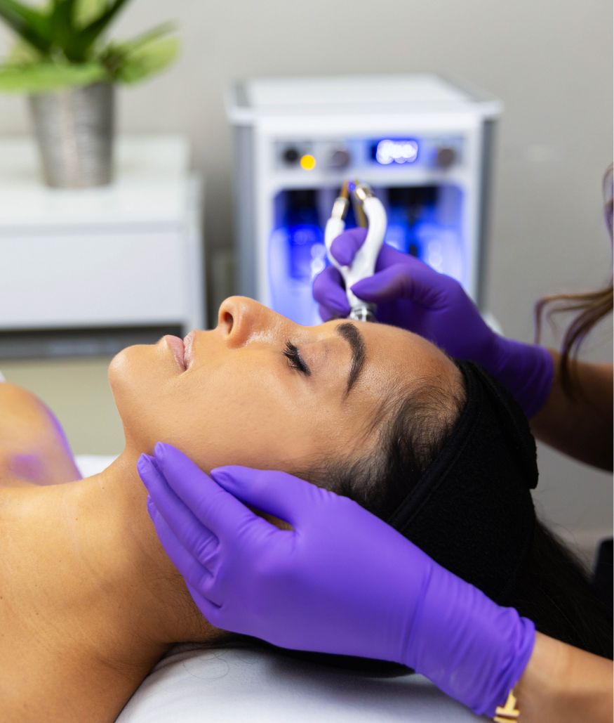 Esthetician performs facial treatment with handheld device on client